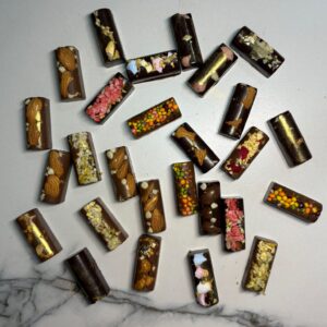 Variétés de chocolats : noir, blanc, lait fourré avec pralines, amandes, bonbons nerds, framboises lyophilisées, marshmallow, noix de cajou